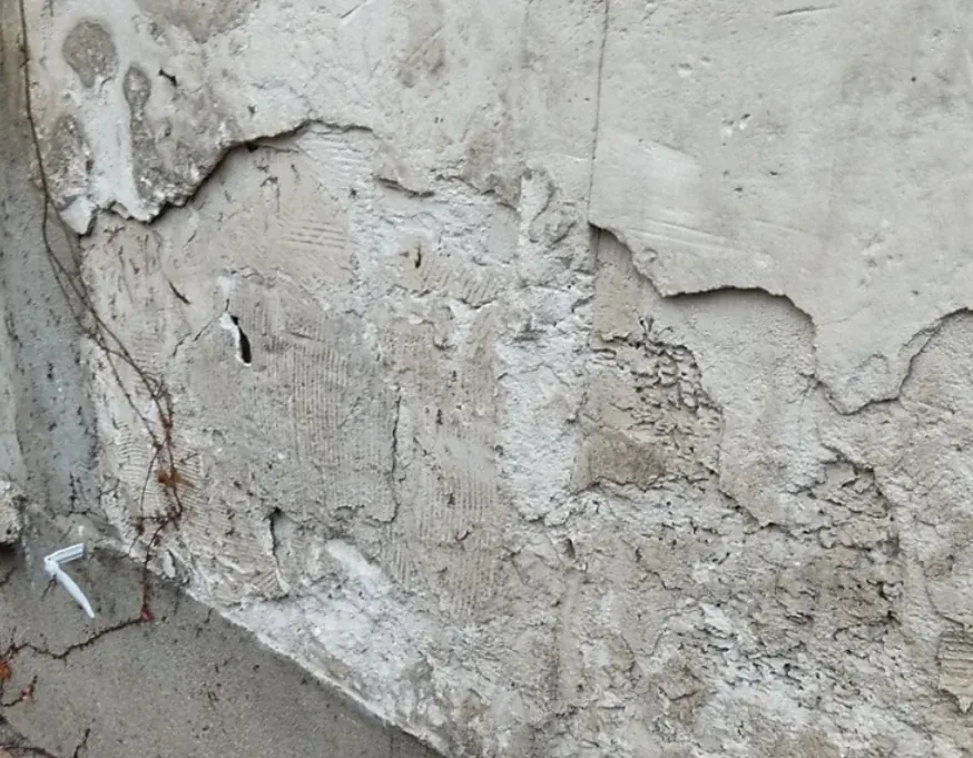 Décollement d'enduit ciment sur mur en pierre